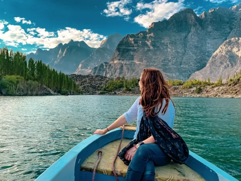 A young girl is sitting in a boat on the lake, admiring the beautiful hills from the boat.Travel to north now